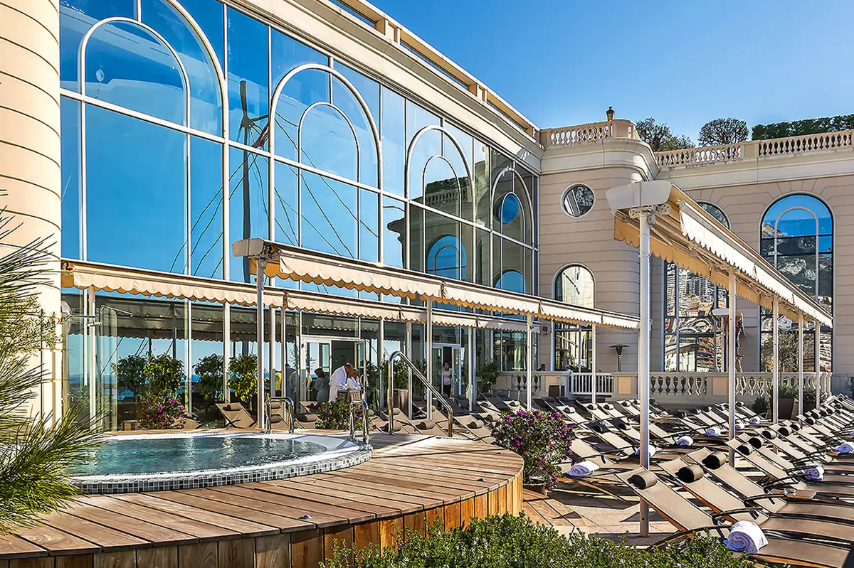 Spa facility with indoor pool, tall windows, and white wooden lounge chairs