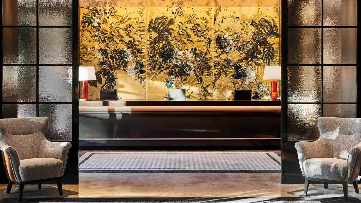 A lobby focal point with gold leaf artwork, sculptural black element, and seating areas
