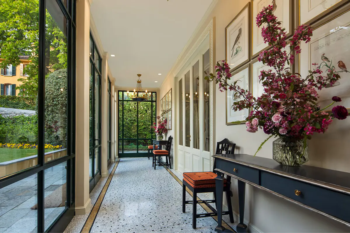 Cream colonnade with flowering plants and lake view through open glass doors