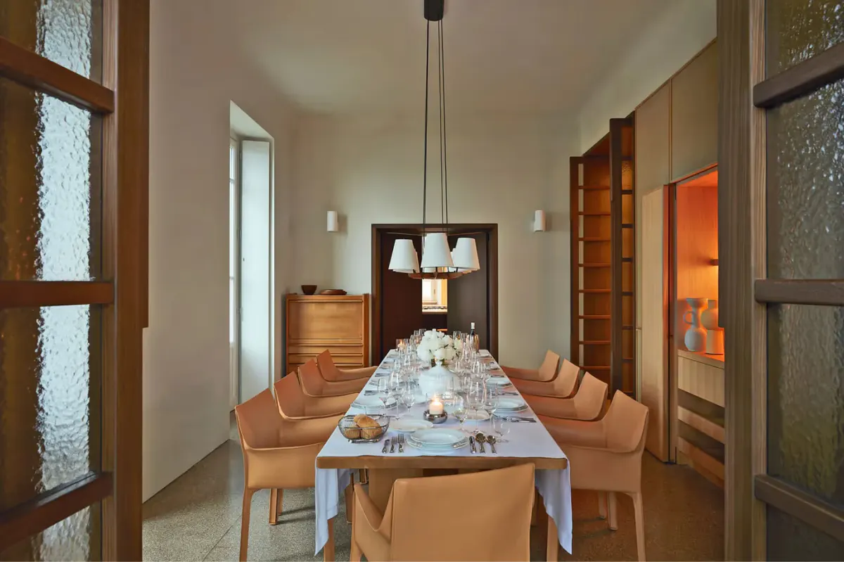 An elegant dining hall with wooden table, high ceilings, and natural light