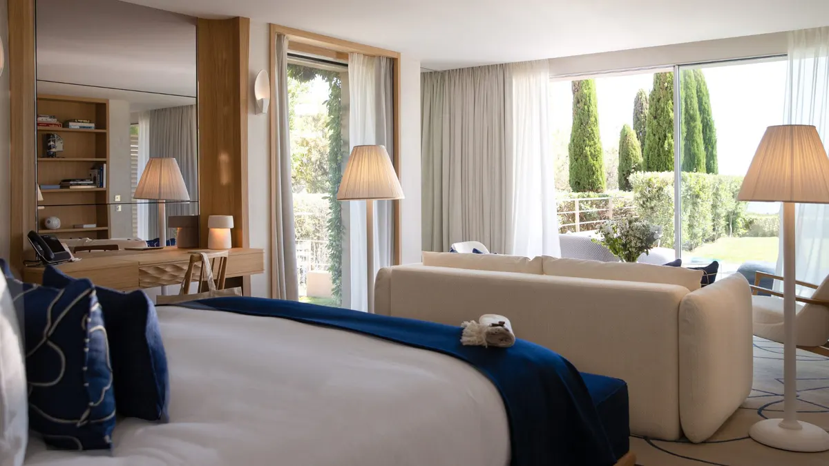 Bedroom with blue-upholstered bed and doors opening to garden