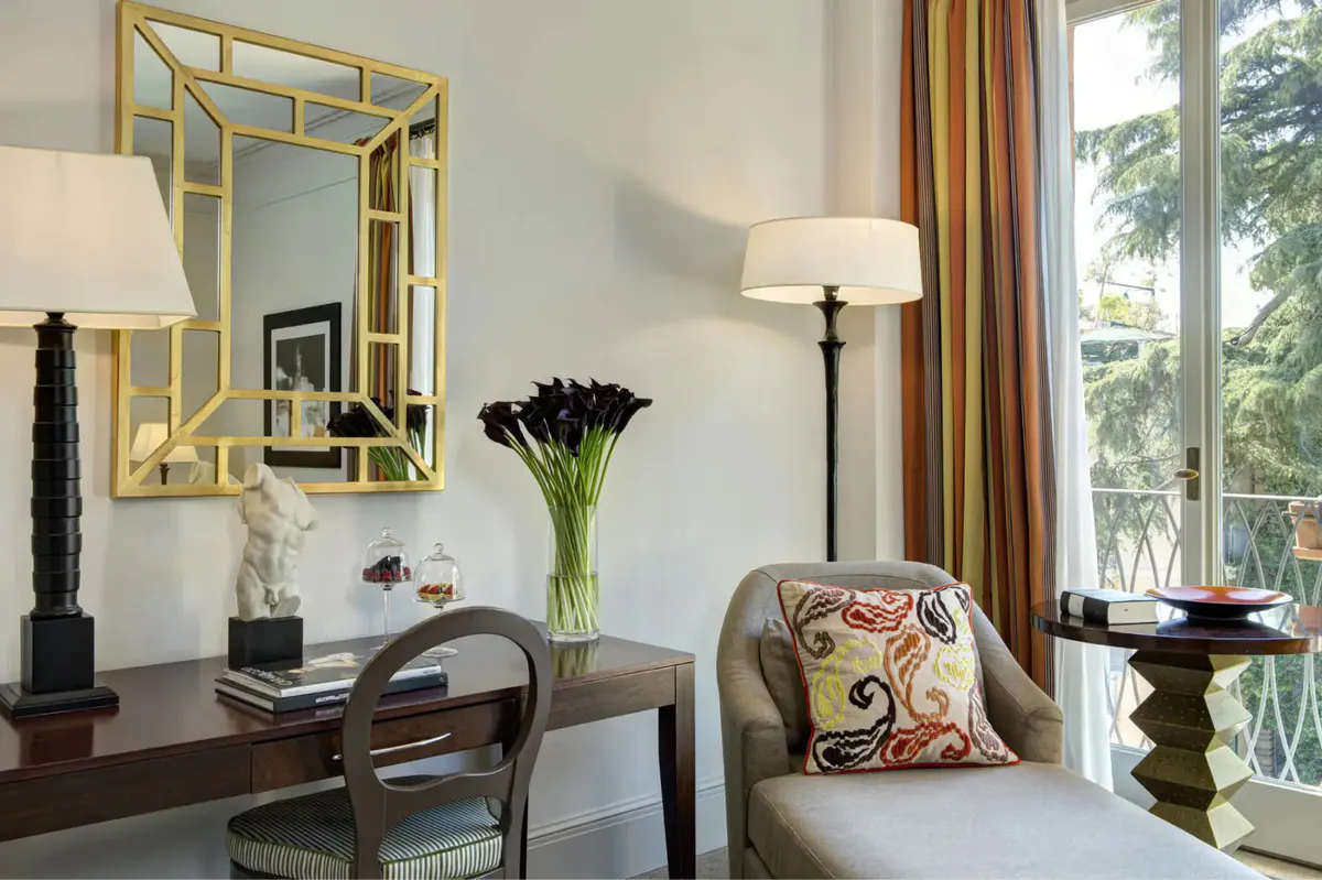 Workspace with brass mirror, upholstered seating, and tall windows overlooking gardens