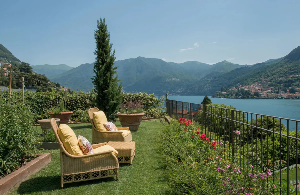 Lawn with rattan seating, tall cypress, and panoramic lake mountain vista