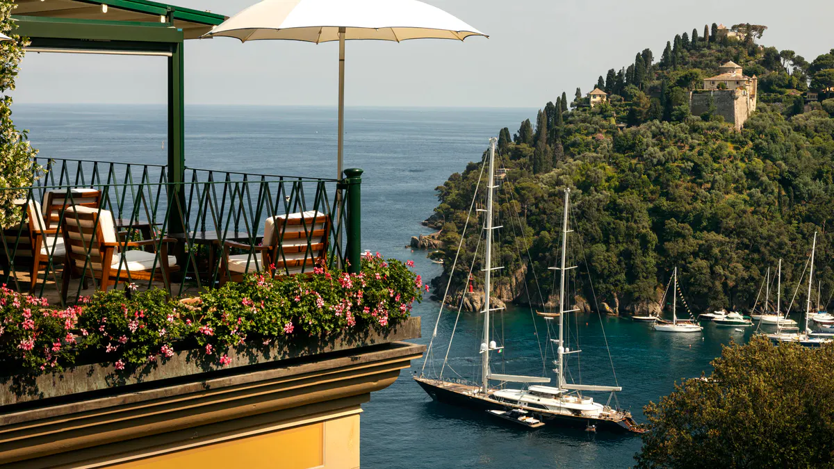 A terrace restaurant overlooking the harbor with sailboats and forested coastline