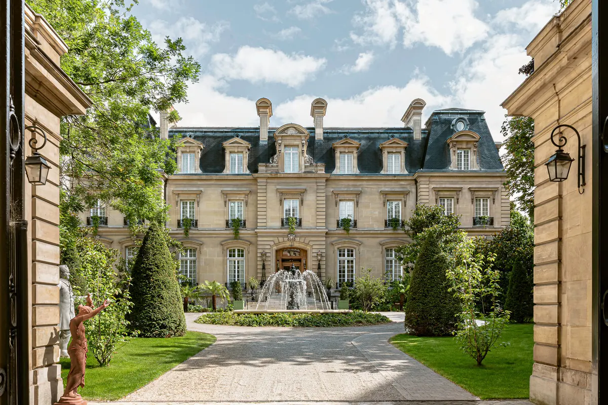 Neoclassical château approached through landscaped courtyard, gravel path leading to ornate entrance