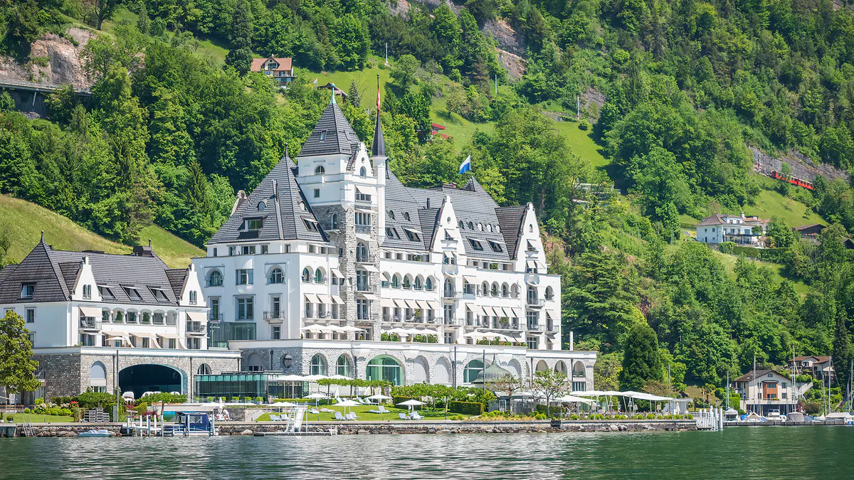 Ornate castle facade viewed from the lake with manicured waterfront
