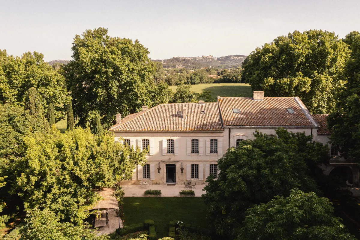 Aerial view of terracotta-roofed manor set among olive trees with countryside vista