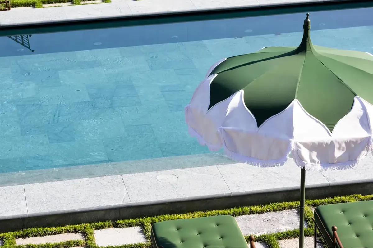 A pool edge detail with striped umbrella and green interior tile visible