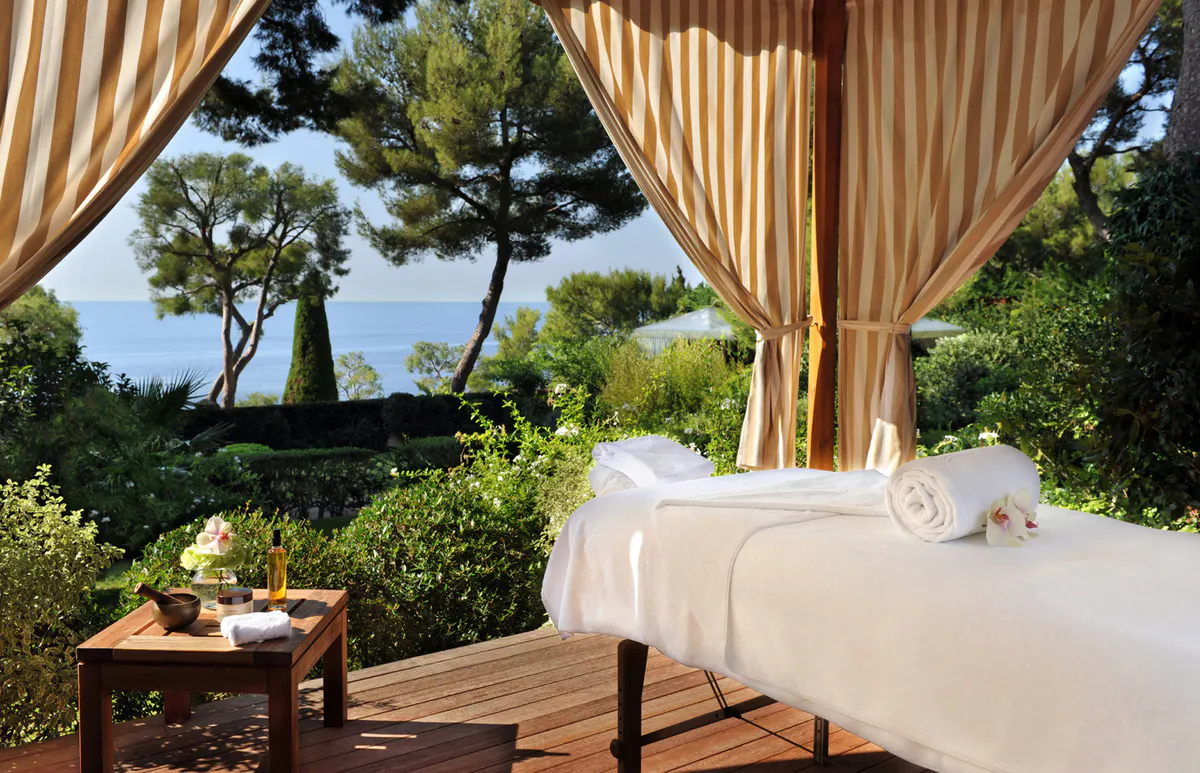 Spa pavilion with massage bed beneath draped curtains and garden view