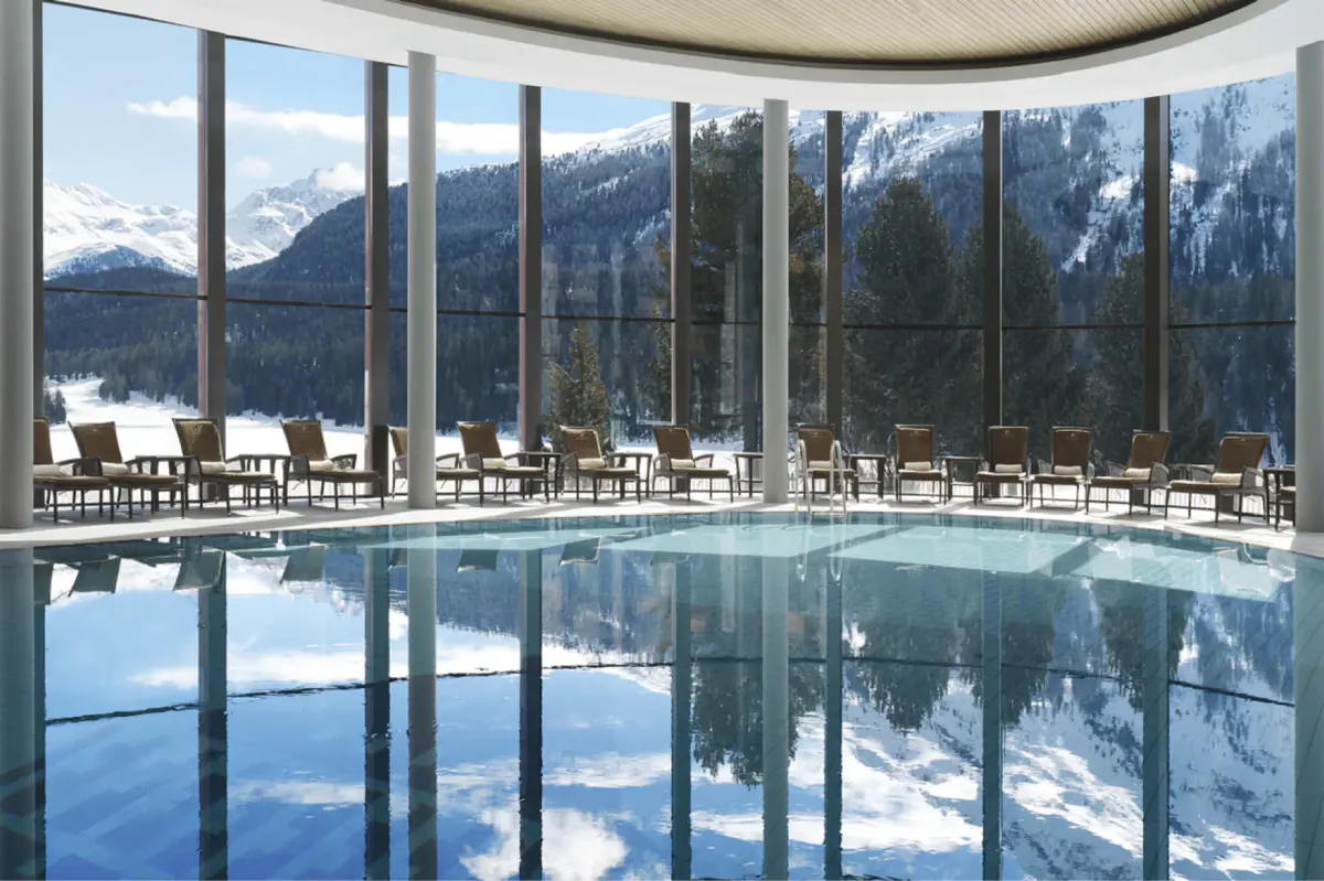 Indoor infinity pool with floor-to-ceiling windows framing mountain landscape