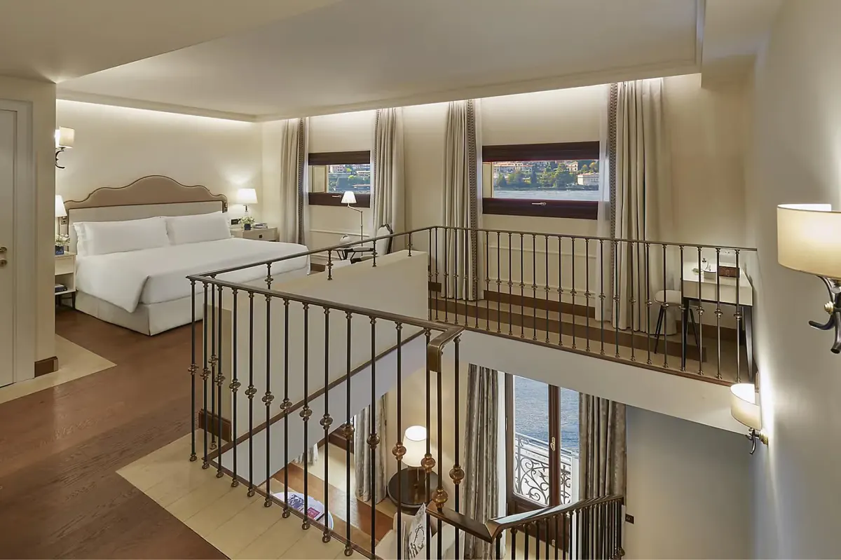 Multi-level suite bedroom with railing mezzanine and expansive lake views through windows
