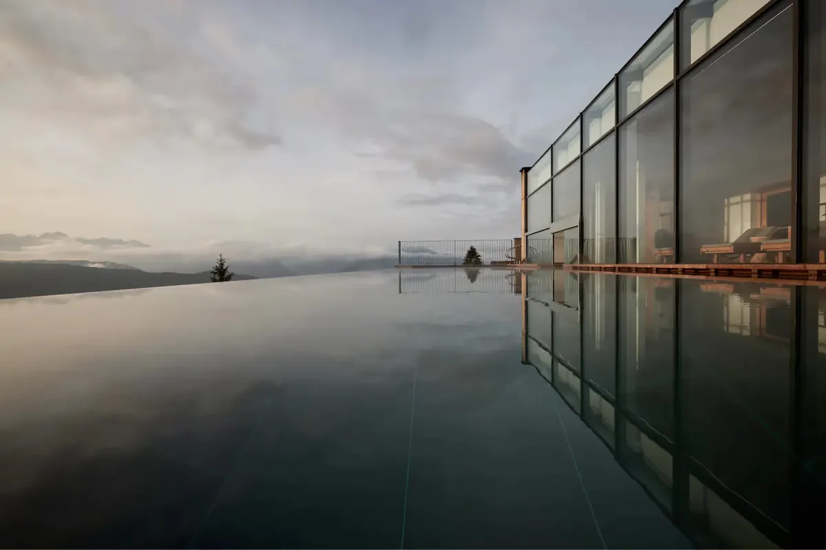 Reflection pool with glass structure overlooking dawn light on distant mountains