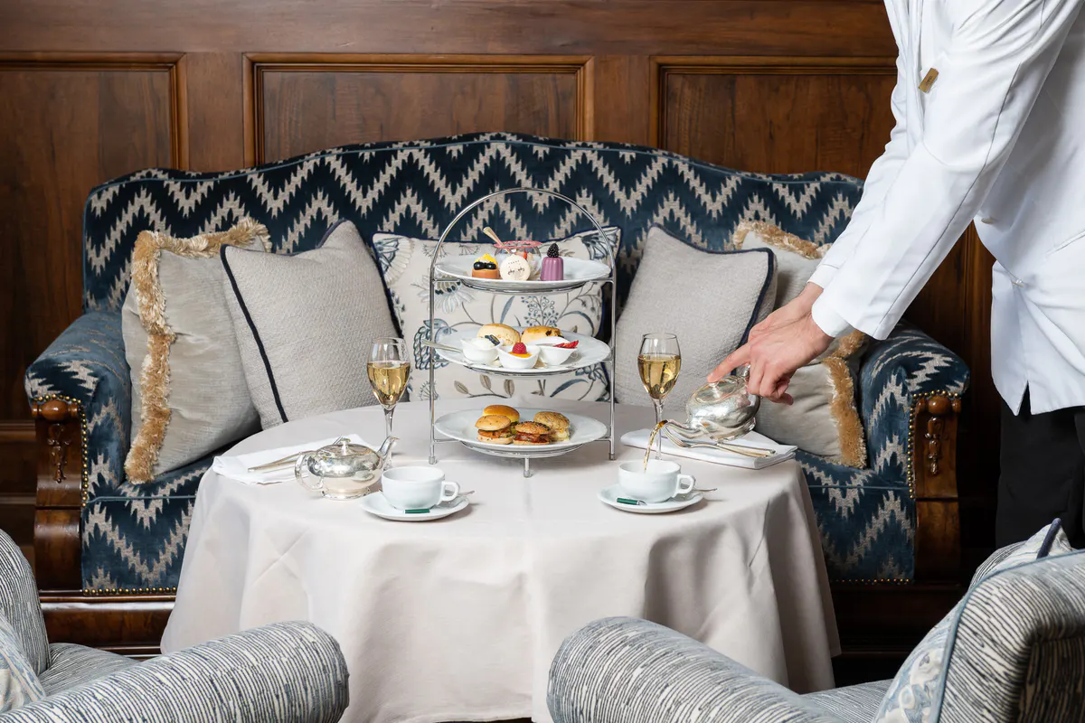 An intimate dining moment with tiered afternoon tea service on patterned banquette seating