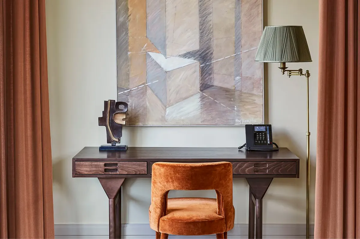 Workspace area with wooden desk, striped upholstered chair, and abstract artwork