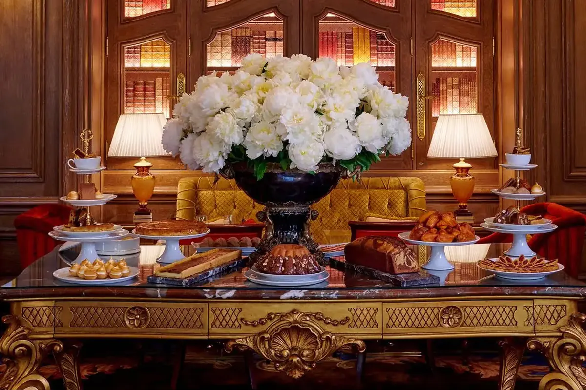 A console table with cream flowers, gilt accessories, and ornate wood paneling