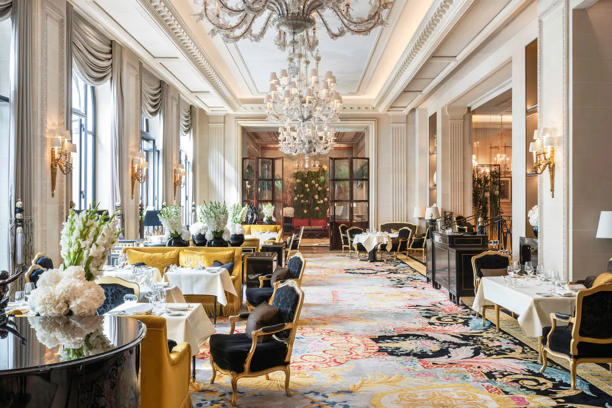 Ornate brass doors opening onto a formally arranged dining room with gold accents